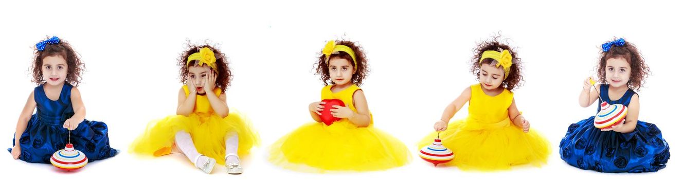 Beautiful little girl is sitting on the floor in the studio. The concept of a happy childhood, beauty and fashion. Isolated on white background.