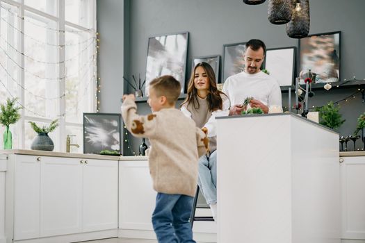 Happy young family spending time together in kitchen at home at Christmas holidays