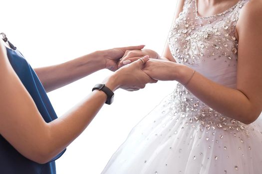 Mom and bride in white dress hold hands, close-up.