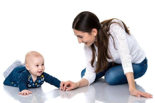 Happy young mother playing with her daughter on the floor on a white background. The concept of a happy childhood, raising a child in the family. Isolated.