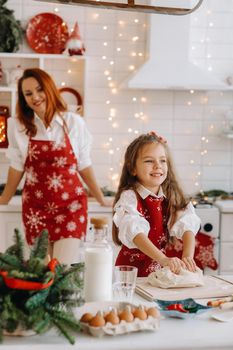 Mom and daughter in the New Year's kitchen together prepare dough for Christmas cookies.