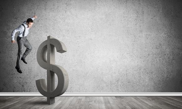 Young furious businessman going to crash with fist stone dollar symbol