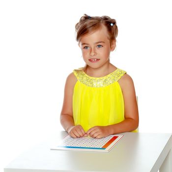A little girl in Montessori kindergarten sits at a table and studies Montessori stuff. The concept of school and preschool education, harmonious development of the child. Isolated on white background.