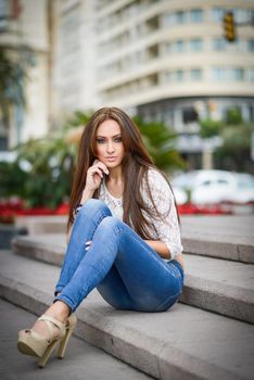 Portrait of a young woman, wearing casual clothes, with long hair in urban background