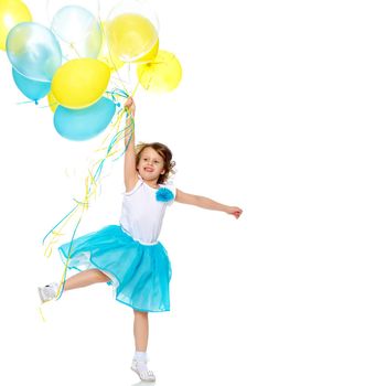 Beautiful little girl in a light blue long skirt, with a bunch of multicolored balloons.She jumps on one foot.Isolated on white background.