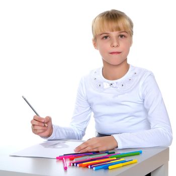 A little girl draws at a table on a piece of paper. The concept of a happy childhood, creativity, learning in school and family. Isolated on white background.