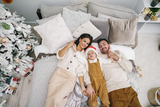 Mother, father and son having fun together on bed on Christmas day