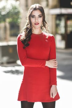 Portrait of young woman in urban background wearing red dress