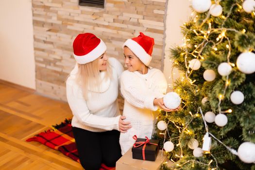 Daughter with her mother near the Christmas tree.