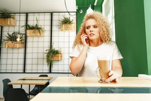 Young beautiful woman talking on the phone in cafeteria close up