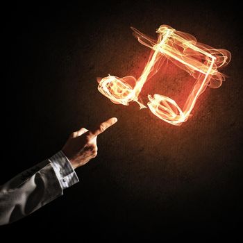 Close up of person hand and fire music symbol on dark background