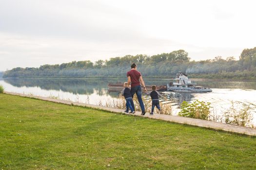 Childhood, family and fatherhood concept - Dad and sons walking together.