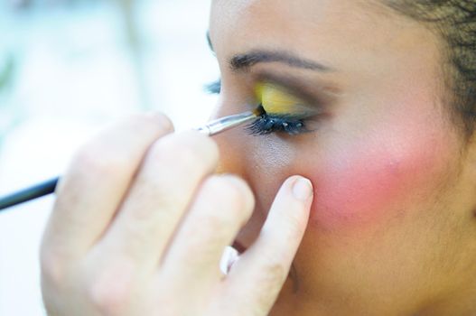 Professional makeup with a beautiful young black woman having touches applied to her make up by a beautician