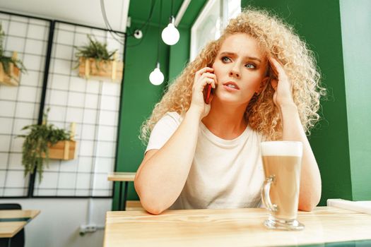 Young beautiful woman talking on the phone in cafeteria close up