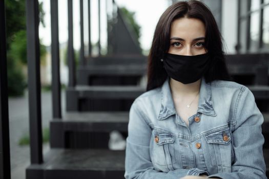 girl in a protective mask on a balcony looks at an empty city.