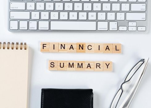 Financial summary concept with letters on wooden cubes. Still life of office workplace with supplies. Flat lay white surface with computer keyboard and notepad. Budget planning, audit and accounting.