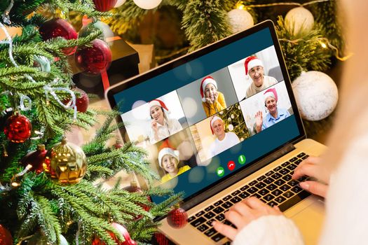Christmas greetings online. a woman in a white sweater and red Santa hat uses a laptop to make video calls to friends, parents, and for online shopping.