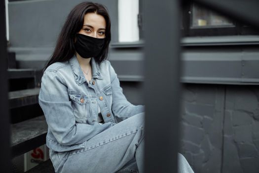 Sad teenager girl in medical mask behind bars. Schools are quarantined due to illness, epidemics. Coronavirus pandemic. Covid 19.