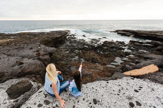 mother and daughter are walking near the ocean on the island of tenerife.