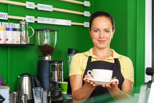 Portrait of a woman barista in coffee shop standing at counter