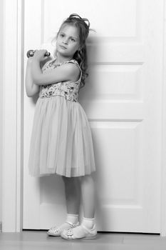 A nice little girl is standing by the door. The concept of family happiness and a home.