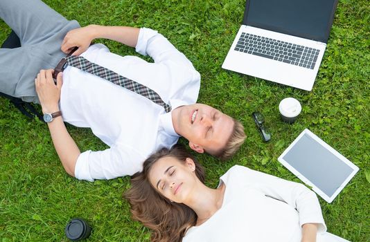 Business persons in the park sit on the grass in the park