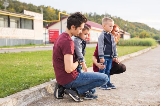 Parenthood, childhood and family concept - Parents and two male children walking at the park and looking on something.