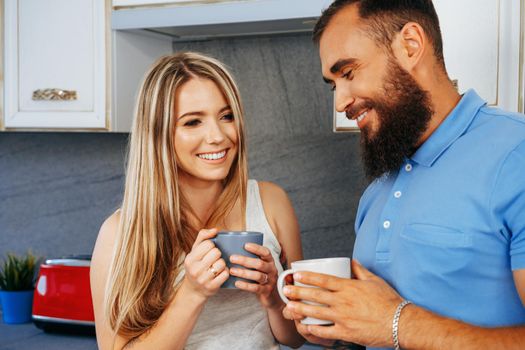 Young woman and man family relaxing with cups of tea at home in kitchen