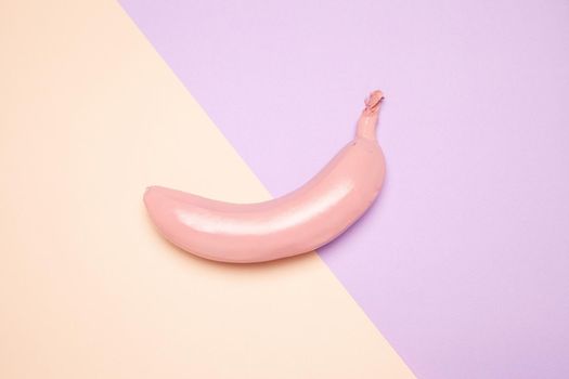 From above of tasty ripe whole banana with shiny pink peel placed on two color background