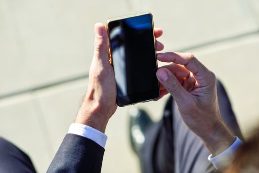 Businessman using his smartphone in the street. Man wearing suit with cellphone.