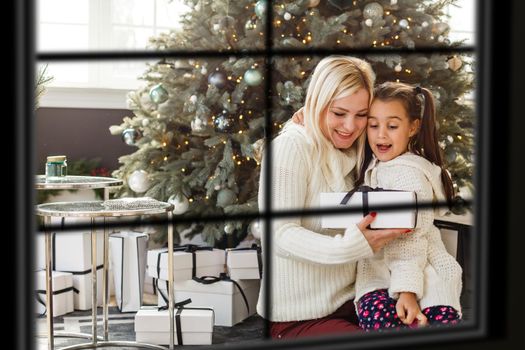 Big family with three children celebrating Christmas at home. Festive dinner at fireplace and Xmas tree. Parent and kids eating at fire place in decorated room. Child lighting advent wreath candle