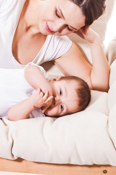 The happy mother leaned over the baby that lies on the couch