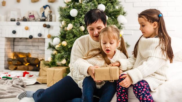 happy young family holding christmas gift and smiling.