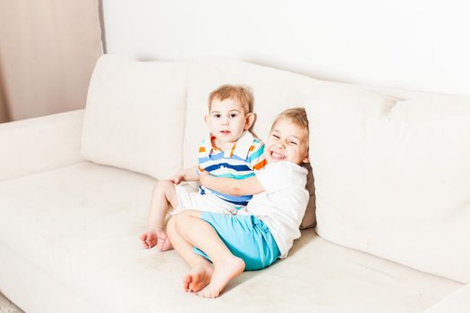 Two brothers hugging on the white couch