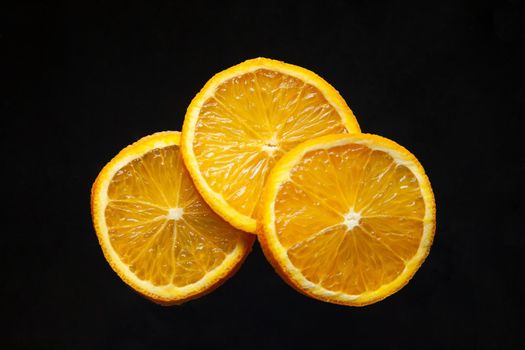 From above pieces of ripe orange full of vitamin C isolated on black background