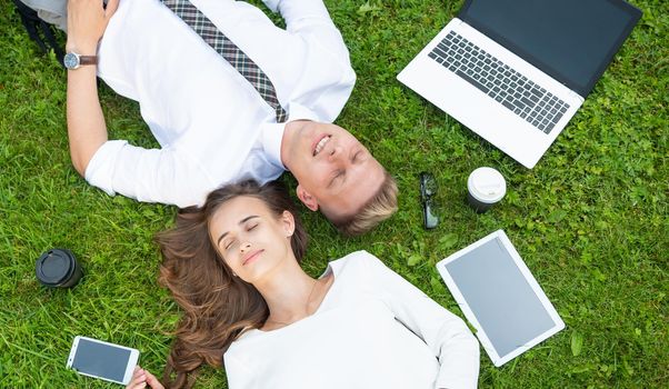 Business persons in the park sit on the grass in the park