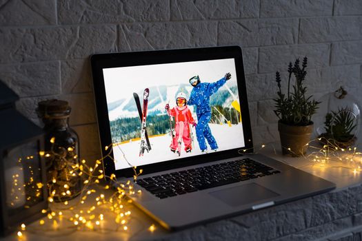 Image of open laptop family and christmas on wooden table in front of christmas tree background.