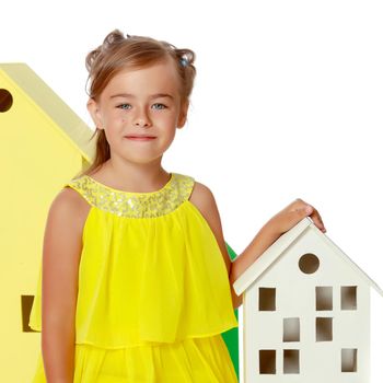 A cute little girl is playing with wooden houses. The concept of family happiness, play, creative development of the child.