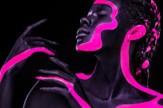 Neon colors. Pink and black body paint. Woman with face art. Young girl with colorful bodypaint. An amazing afro american model with makeup