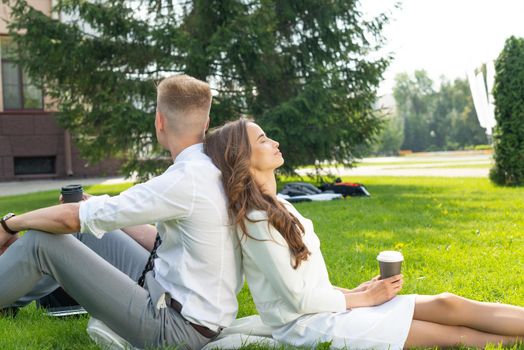 Business persons in the park sit on the grass in the park