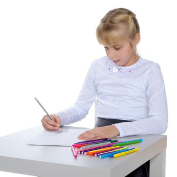 A little girl draws at a table on a piece of paper. The concept of a happy childhood, creativity, learning in school and family. Isolated on white background.