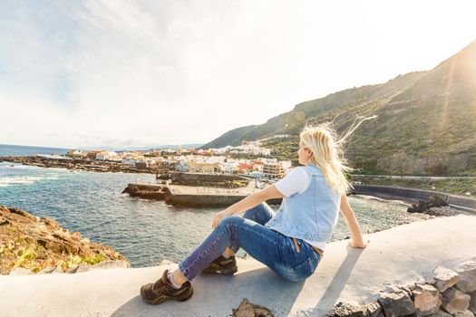 Young girl smiling and speaking consulting and giving instruction with voice recognition. Woman with audio recording in smart phone in the seaside in Garachico, Tenerife