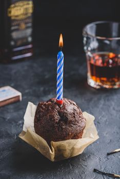 Chocolate muffin with birthday candle on dark concrete background