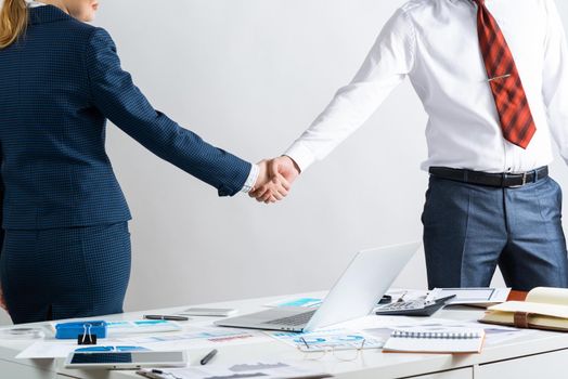 Businessman and businesswoman handshaking after good deal. Business consultation and cooperation in office. Corporate teamwork and partnership. Businesspersons greeting or finishing successful meeting