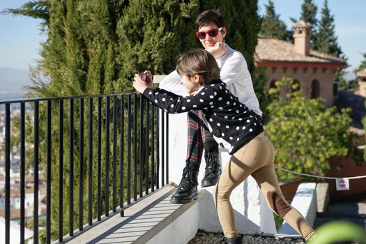 Little girl and her middle-aged mother photographing the views from the Rodriguez Acosta Foundation. Granada, Andalusia, Spain