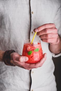 Glass of watermelon cocktail with gin and soda in hands