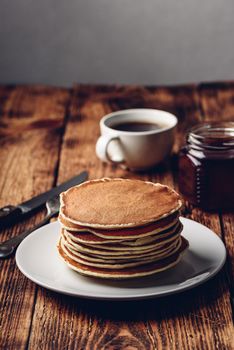 Stack of pancakes on white plate over wooden surface