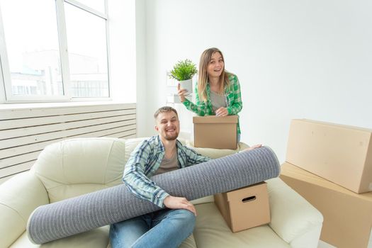 Satisfied cheerful young couple strong man and pretty woman holding their things in their hands sitting in the living room of a new apartment. Housewarming concept