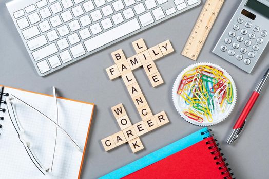 Business motivation concept with words from cubes. Still life of office workplace with crossword. Flat lay grey surface with computer keyboard and stationery. Strategy planning and business analytics.