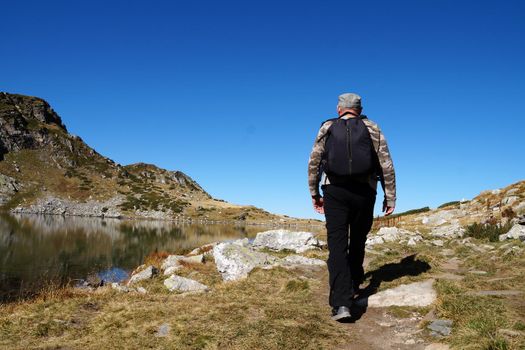 a man with a backpack goes to the mountains, back view
